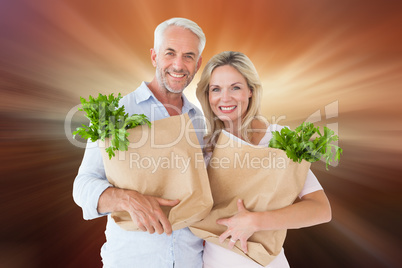 Composite image of happy couple carrying paper grocery bags
