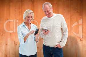 Composite image of happy mature couple using their smartphones