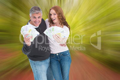 Composite image of casual couple showing their cash