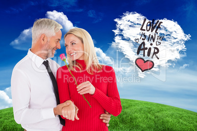 Composite image of handsome man giving his wife a pink rose