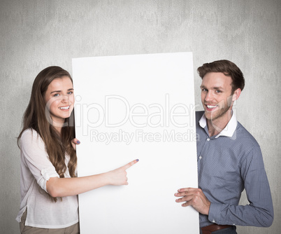 Composite image of happy young couple with blank board