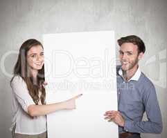 Composite image of happy young couple with blank board