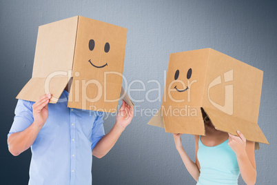 Composite image of couple wearing emoticon face boxes on their h