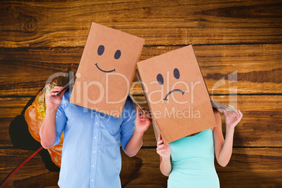 Composite image of couple wearing sad face boxes on their heads