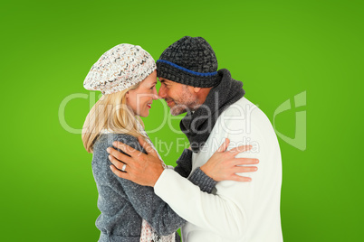 Composite image of happy couple in winter fashion embracing