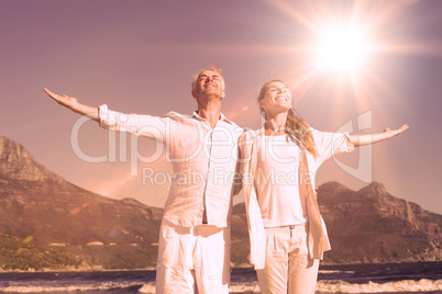 Happy couple standing with arms outstretched at the beach