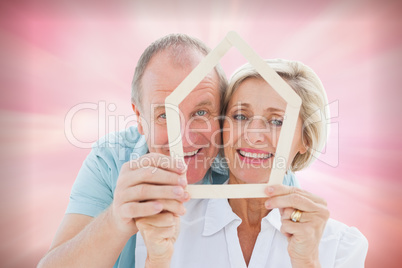 Composite image of happy older couple holding house shape