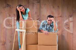 Composite image of stressed young couple with moving boxes