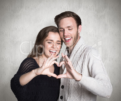 Composite image of happy couple forming heart with hands