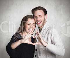 Composite image of happy couple forming heart with hands