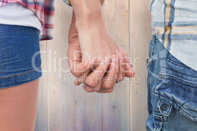 Composite image of couple in check shirts and denim holding hand