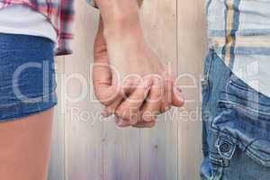 Composite image of couple in check shirts and denim holding hand