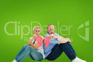 Composite image of sad mature couple holding a broken heart