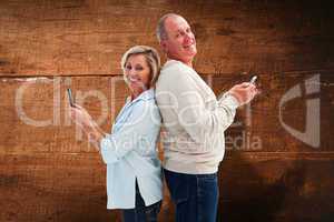 Composite image of happy mature couple using their smartphones