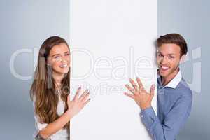 Composite image of happy young couple with blank board