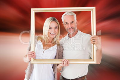 Composite image of happy couple holding a picture frame