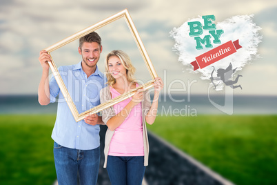 Composite image of attractive young couple holding picture frame