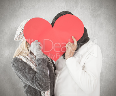 Composite image of couple in winter fashion posing with heart sh