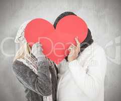 Composite image of couple in winter fashion posing with heart sh