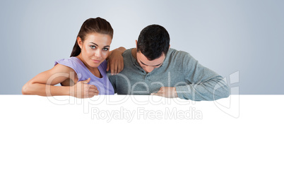 Composite image of young couple looking over a wall