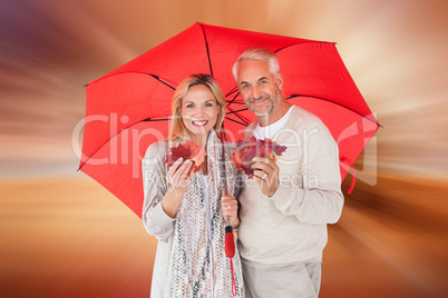 Composite image of smiling couple showing autumn leaves under um