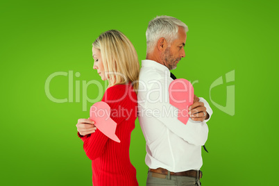 Composite image of couple holding two halves of broken heart