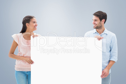 Composite image of attractive young couple smiling and holding p