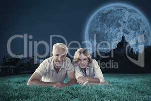 Composite image of happy couple lying smiling at camera