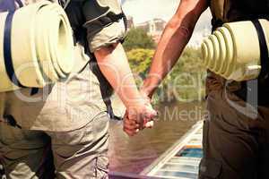 Composite image of hitch hiking couple standing holding hands on