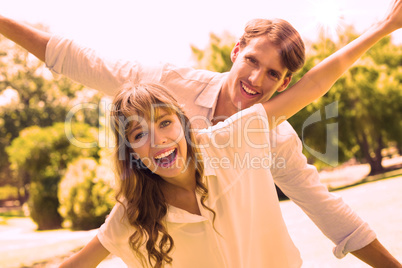 Attractive couple smiling at camera and spreading arms in the pa