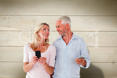 Composite image of happy couple texting on their smartphones