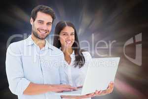 Composite image of attractive young couple holding their laptop