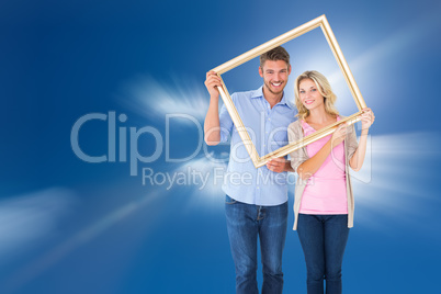 Composite image of attractive young couple holding picture frame