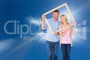 Composite image of attractive young couple holding picture frame