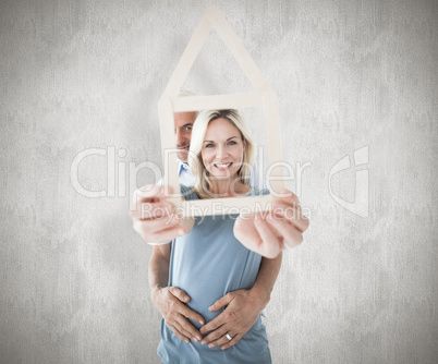 Composite image of happy couple holding house outline