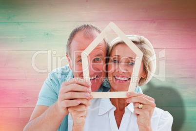 Composite image of happy older couple holding house shape