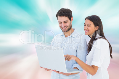 Composite image of attractive young couple holding their laptop
