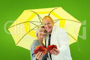 Composite image of happy mature couple showing autumn leaves und