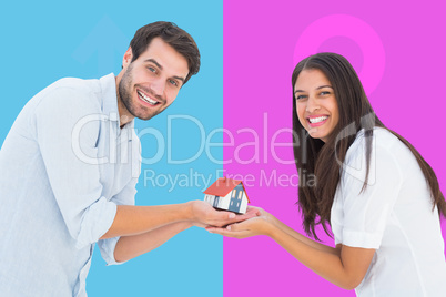 Composite image of attractive young couple holding a model house