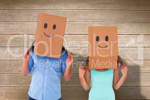 Composite image of couple wearing emoticon face boxes on their h