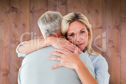 Composite image of unhappy blonde hugging her husband