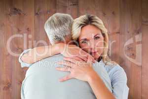 Composite image of unhappy blonde hugging her husband