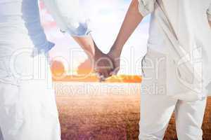 Composite image of couple on the beach looking out to sea holdin