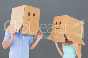 Composite image of couple wearing emoticon face boxes on their h