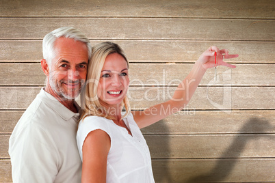 Composite image of happy couple showing their new house key