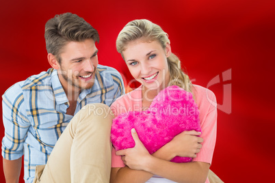 Composite image of attractive young couple sitting holding heart