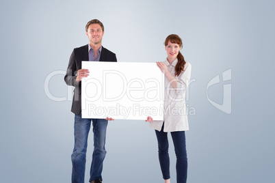 Composite image of smiling couple holding large sign