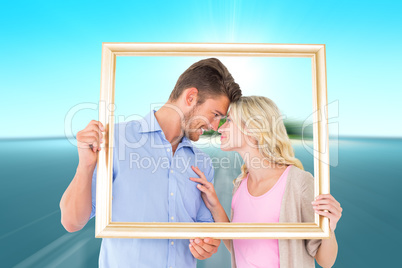 Composite image of attractive young couple holding picture frame