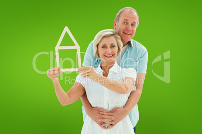 Composite image of happy older couple holding house shape