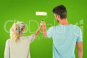 Composite image of young couple painting with roller